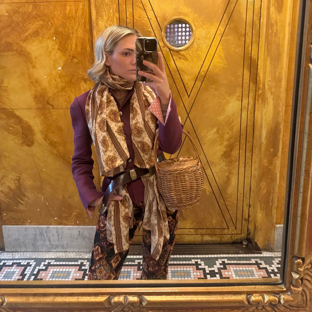 Woman taking a mirror selfie with the Celina Pareo in front of a large gold door.