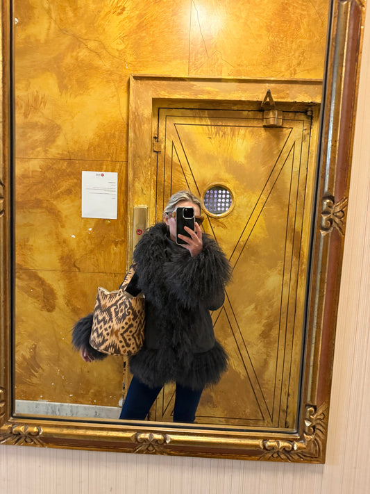 Person taking a mirror selfie in front of a gold door.